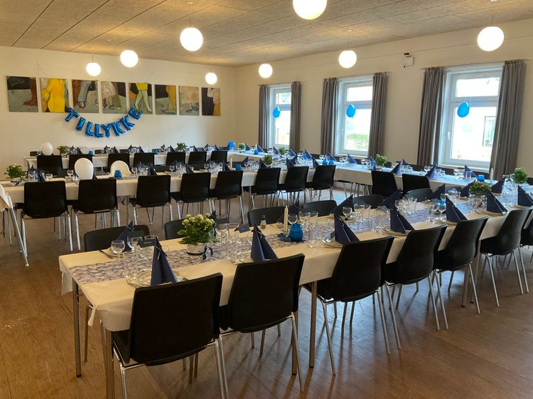 Festsalen dækket op til fest med hestesko og lange borde